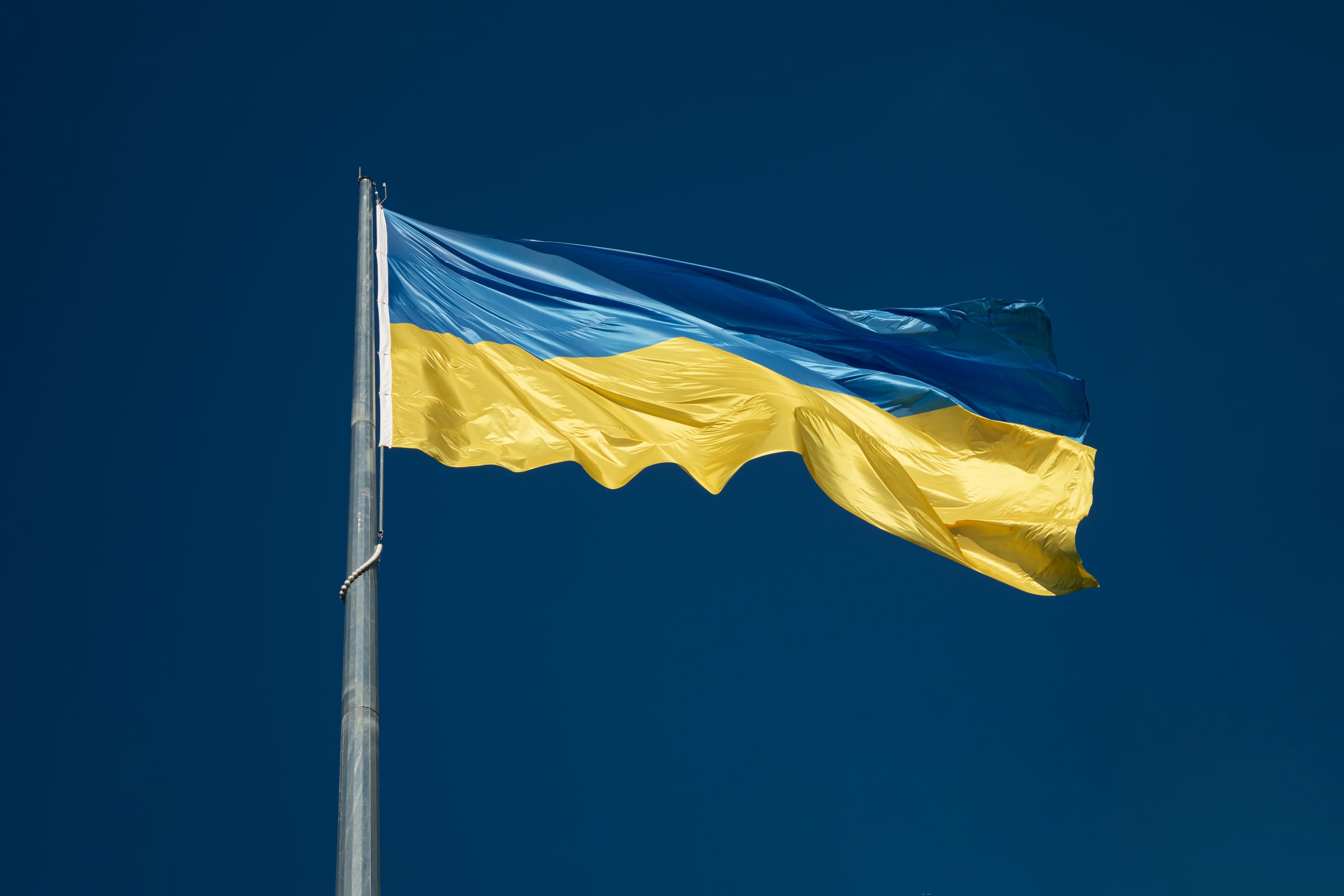 Ukrainas flagg i blått og gult mot en mørk blå himmel.
